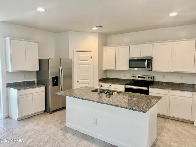 a kitchen with stainless steel appliances granite countertop a refrigerator stove microwave and sink