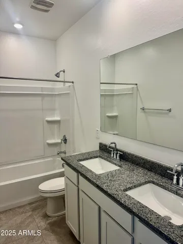 a bathroom with a granite countertop sink a toilet and a bathtub