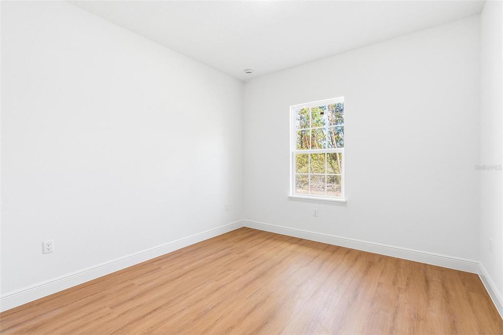 5227 Southwest 165th St Road Ocala, FL 34473 - Photo 16 of 37 a view of an empty room with wooden floor and a window