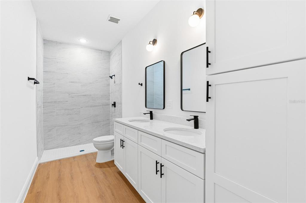 5227 Southwest 165th St Road Ocala, FL 34473 - Photo 20 of 37 a bathroom with a double vanity sink toilet mirror and shower