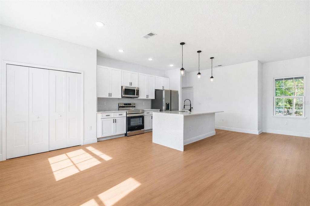 5227 Southwest 165th St Road Ocala, FL 34473 - Photo 4 of 37 a view of kitchen with stainless steel appliances granite countertop a stove top oven a sink dishwasher and a refrigerator with wooden floor