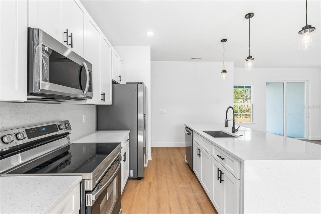 5227 Southwest 165th St Road Ocala, FL 34473 - Photo 9 of 37 a kitchen with stainless steel appliances a stove a sink a microwave and a refrigerator