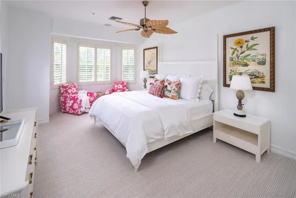 a bedroom with a bed chandelier painting on the wall and a window