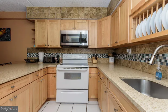 a kitchen with granite countertop a sink a stove and cabinets