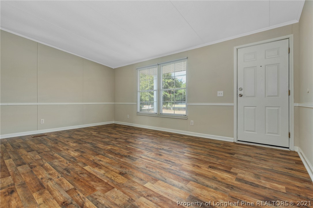 6544 Sandy Creek Road Stedman, NC 28391 - Photo 5 of 32 a view of an empty room with wooden floor and a window