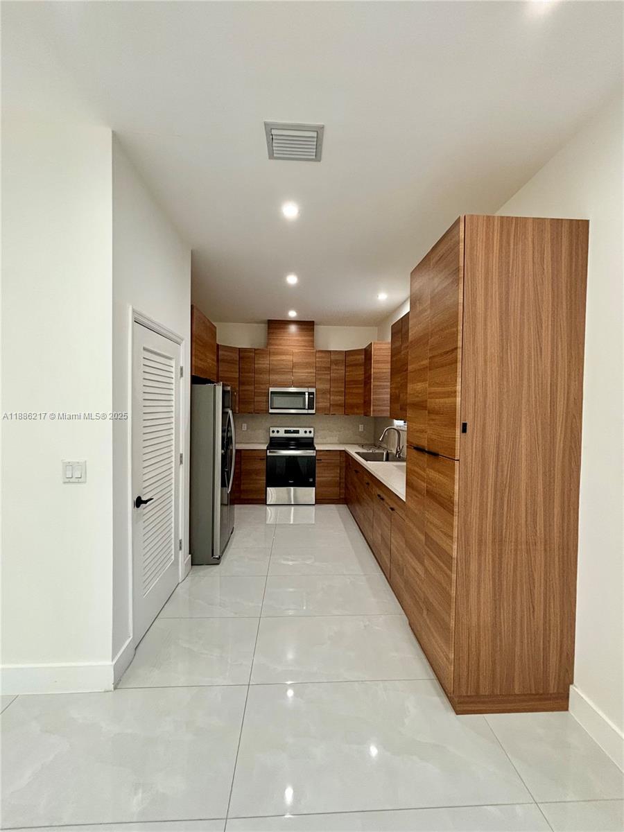 a open kitchen with stainless steel appliances kitchen island granite countertop a refrigerator and a sink