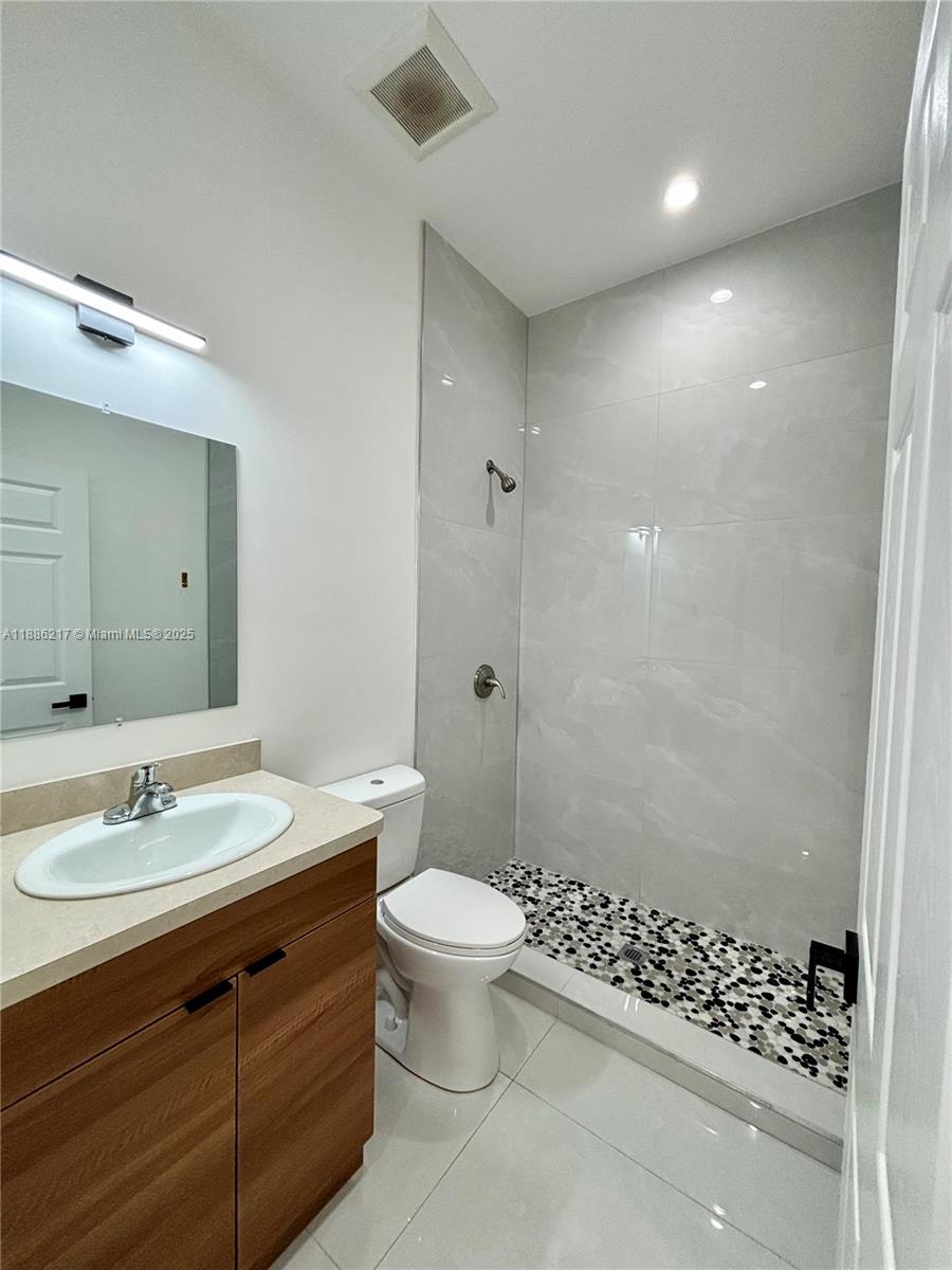 5737 Cleveland Street, Unit 2 Hollywood, FL 33021 - Photo 6 of 18 a bathroom with a sink a toilet a shower and a mirror