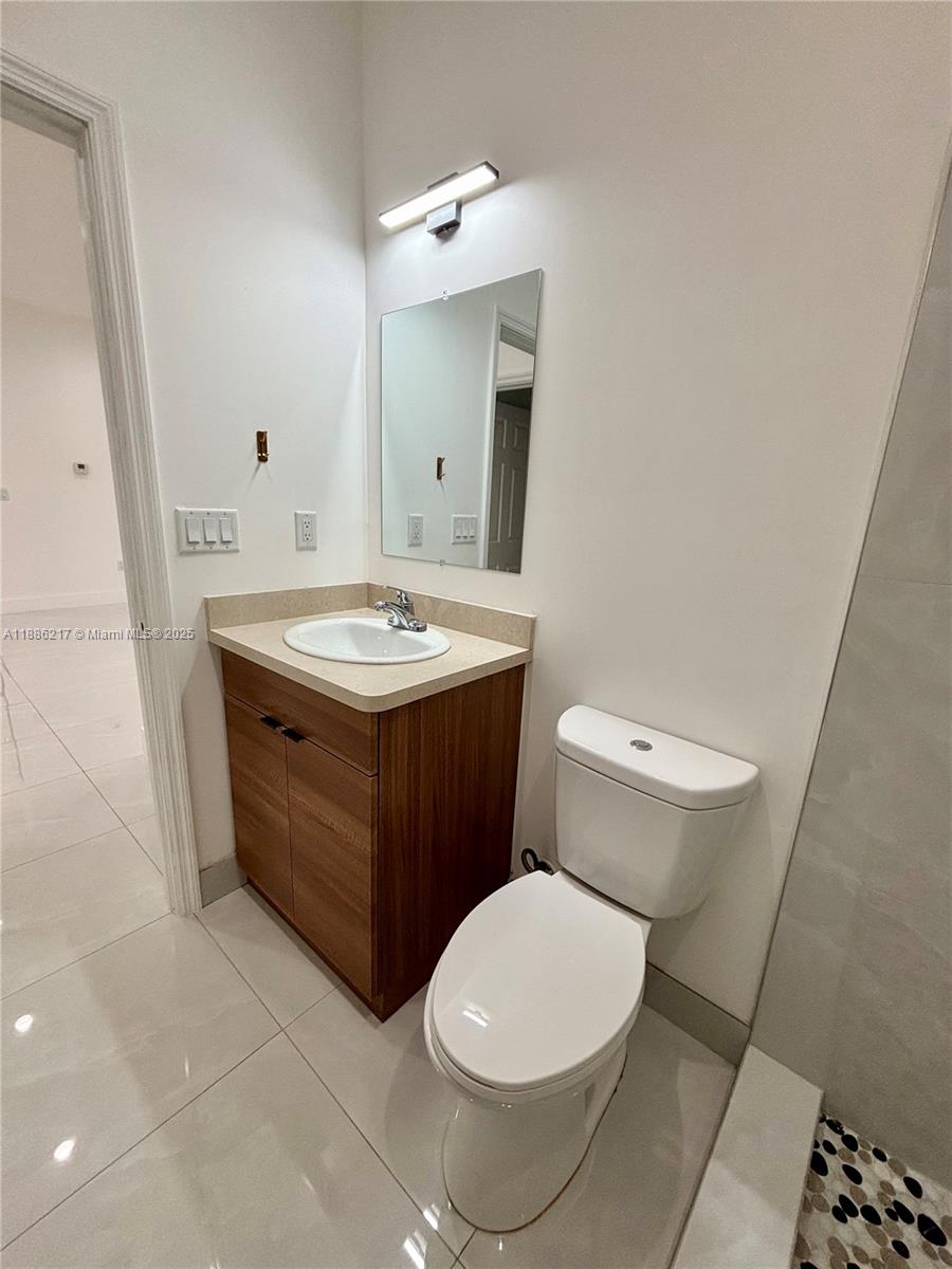 5737 Cleveland Street, Unit 2 Hollywood, FL 33021 - Photo 7 of 18 a bathroom with a toilet a sink and a mirror