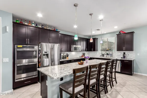 a kitchen with stainless steel appliances kitchen island granite countertop a dining table and chairs