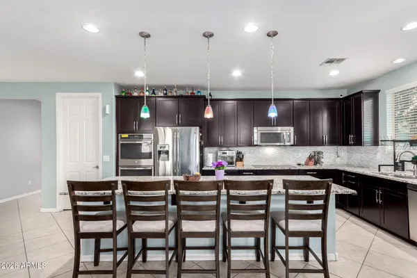 a kitchen with stainless steel appliances kitchen island granite countertop a table chairs sink and microwave