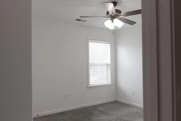 an empty room with a window and a fan