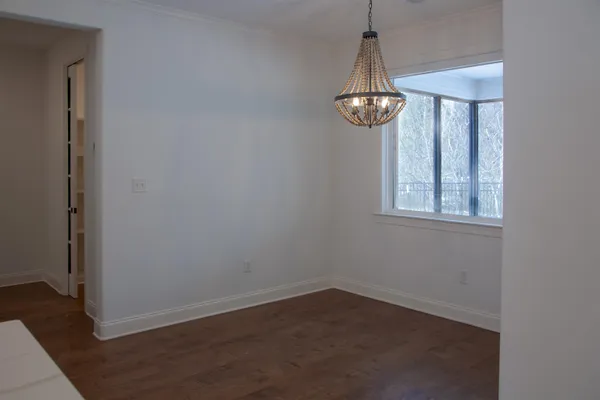 an empty room with wooden floor chandelier and windows