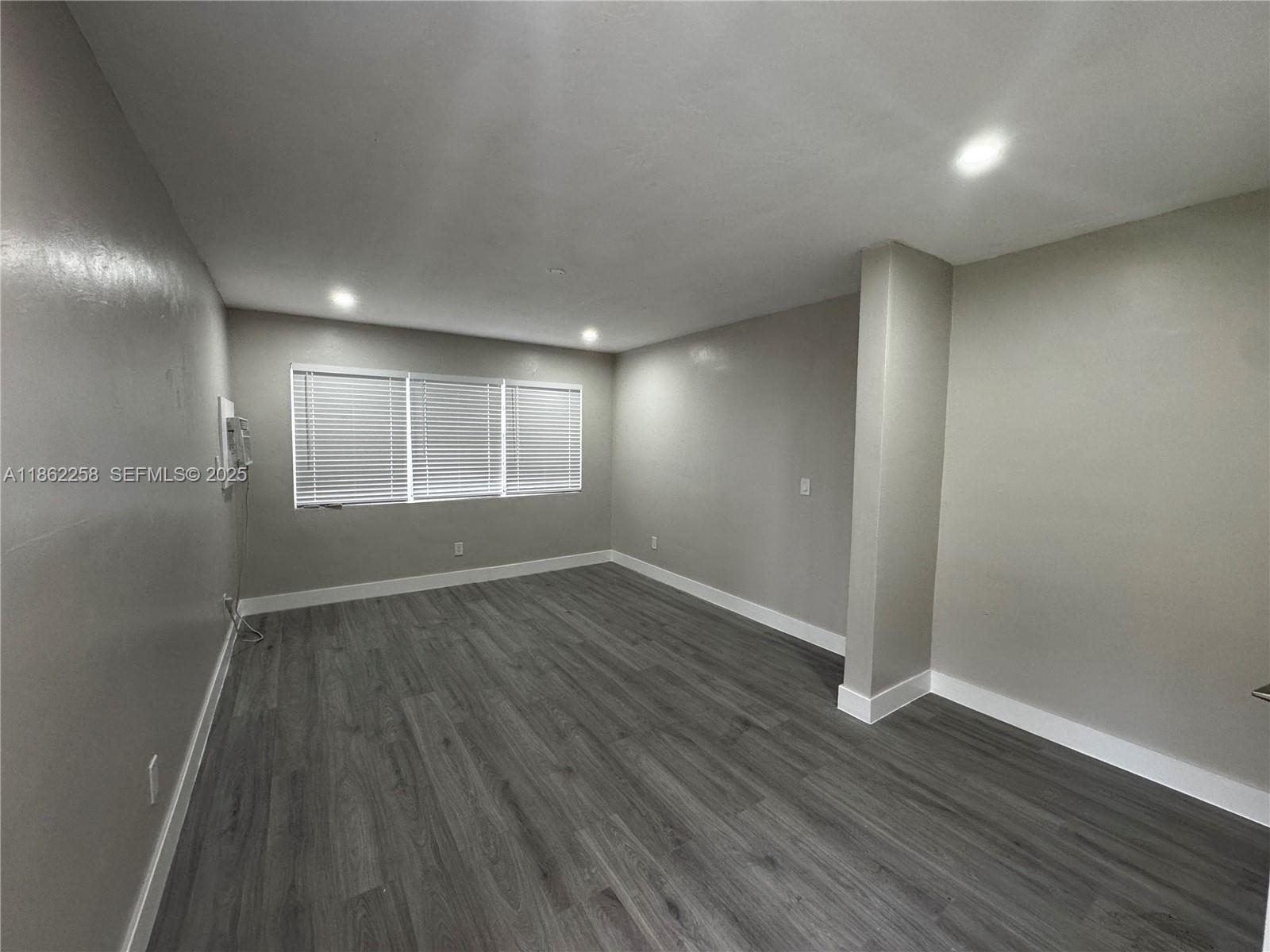 2377 Northwest 35th Street, Unit UTILITIES Miami, FL 33142 - Photo 3 of 9 an empty room with wooden floor and windows