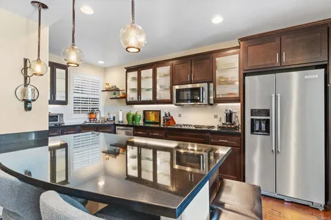 a kitchen with kitchen island granite countertop a sink cabinets and stainless steel appliances