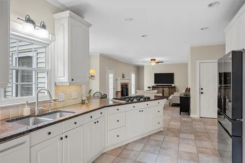 a large white kitchen with a sink and a large window