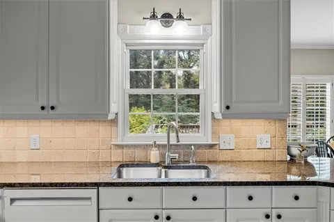 a kitchen with granite countertop white cabinets and a window