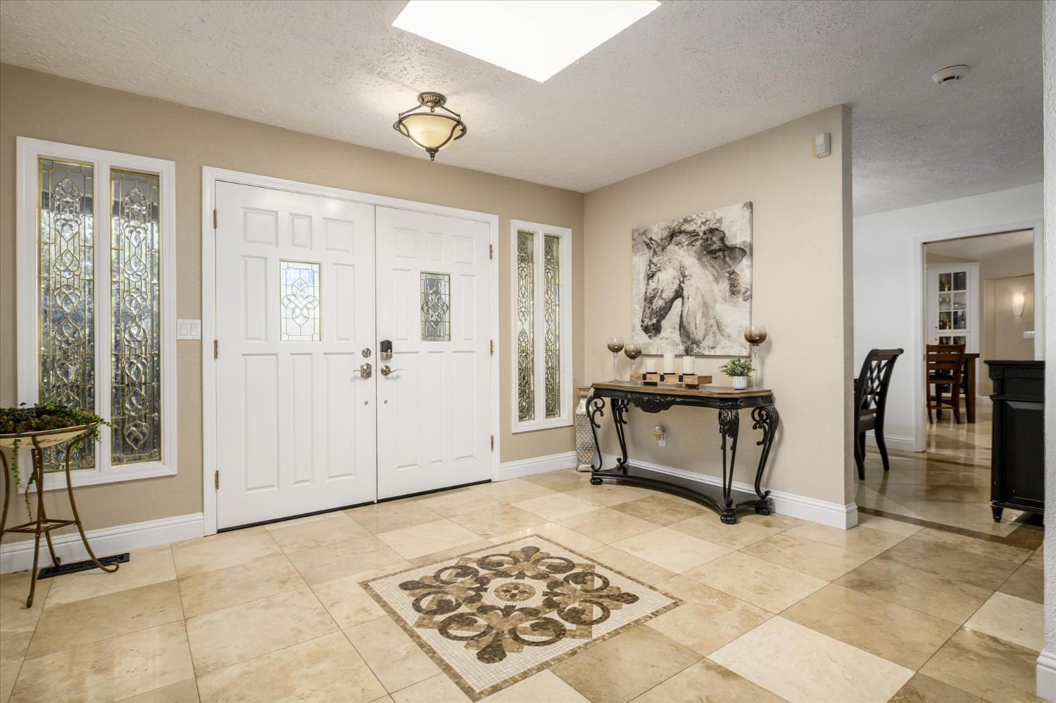3165 Oakwood Road Cameron Park, CA 95682 - Photo 4 of 55 A beautifully designed foyer welcomes you home, featuring a striking tile inlay that sets the stage for the travertine flooring that gracefully carries through the formal dining room and kitchen.