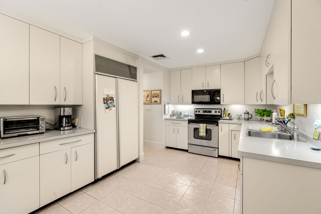 228 Allandale Road, Unit 1A Boston, MA 02467 - Photo 10 of 17 a kitchen with granite countertop white cabinets and white appliances