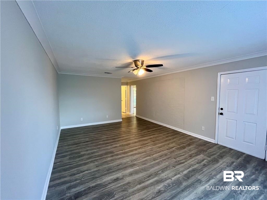 8636 Boe Road Irvington, AL 36544 - Photo 9 of 22 Spare room featuring dark wood-style floors, ceiling fan, crown molding, and a textured ceiling