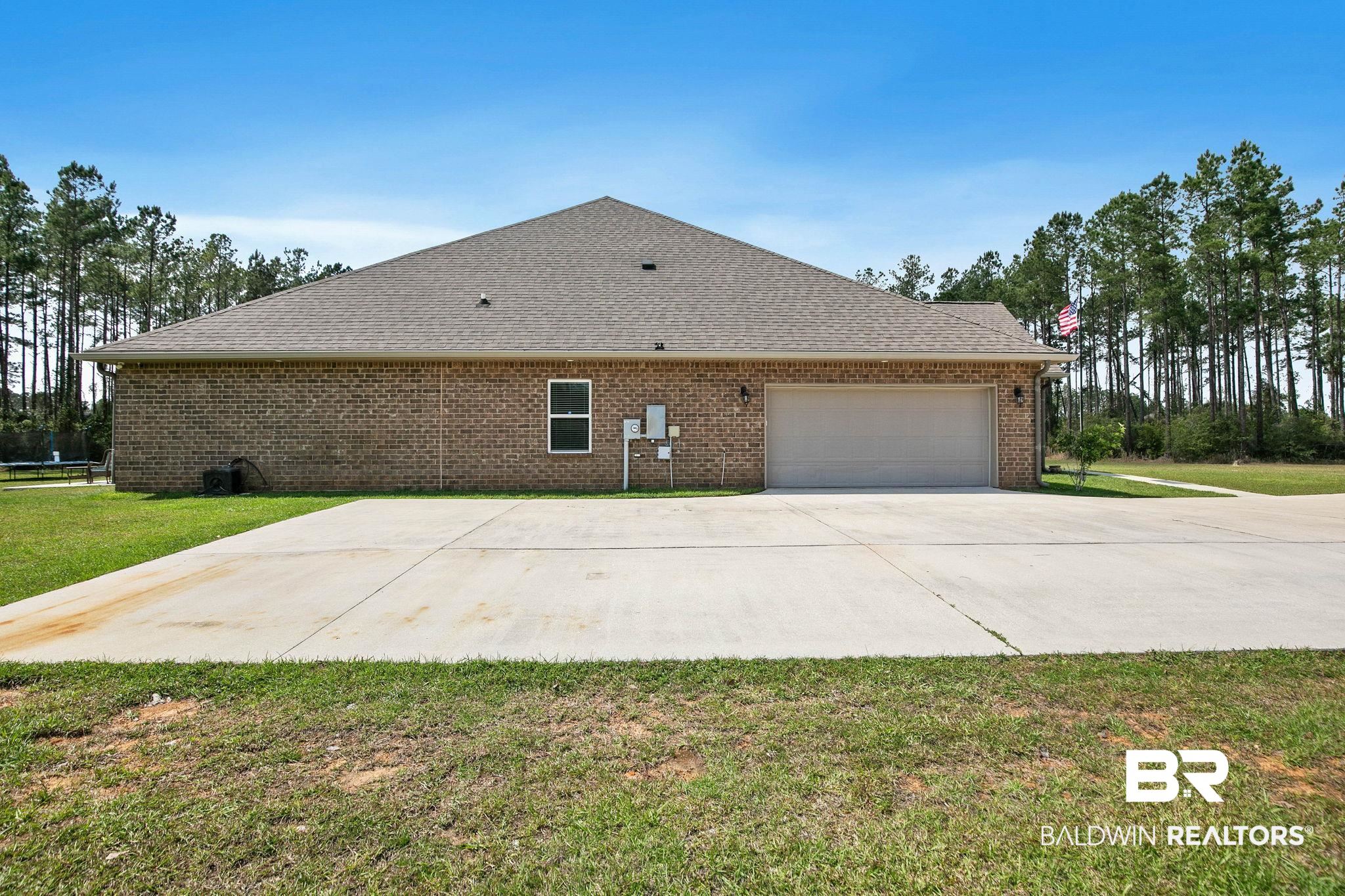 12750 B Jenkins Pit Road Daphne, AL 36527 - Photo 63 of 89 View of home's exterior featuring a lawn, an attached garage, brick siding, and concrete driveway