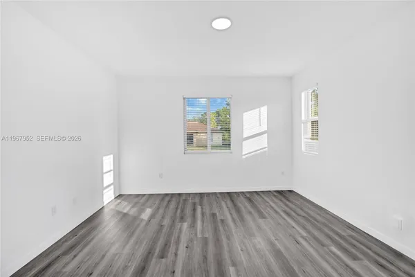 an empty room with wooden floor and windows