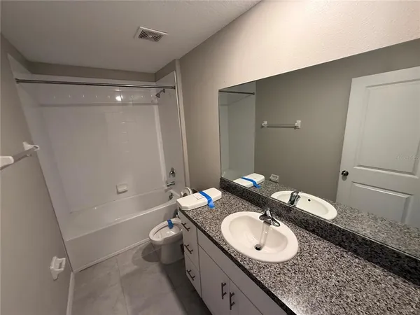 a bathroom with a granite countertop double vanity sink a mirror and a toilet