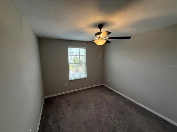an empty room with a window a chandelier fan and windows