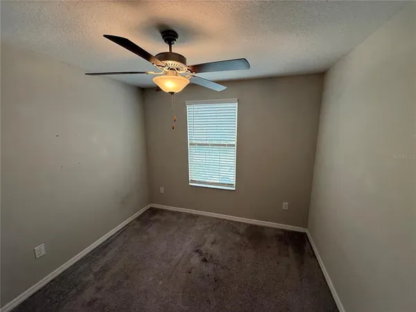 an empty room with a window and a fan