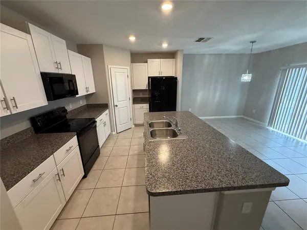 a kitchen with a sink a microwave a refrigerator and chairs