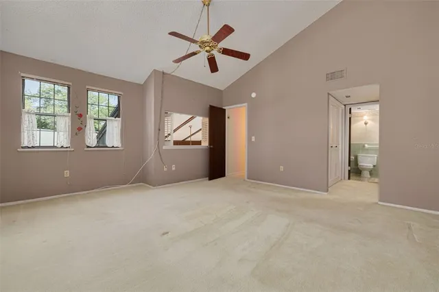 an empty room with ceiling fan and windows