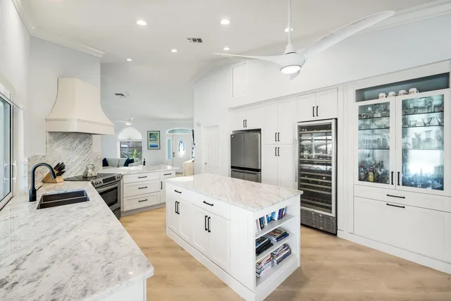 a kitchen that has a lot of white cabinets and stainless steel appliances