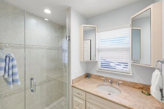 a bathroom with a granite countertop sink a mirror and a shower