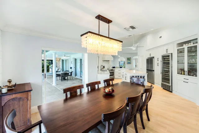 a view of a dining room and livingroom with furniture wooden floor a rug a painting and a chandelier