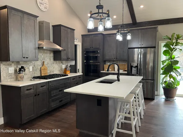 a kitchen with stainless steel appliances a table chairs in it and wooden floors