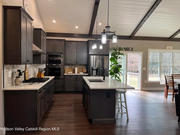 a kitchen with stainless steel appliances kitchen island granite countertop a stove a sink a refrigerator cabinets and wooden floor