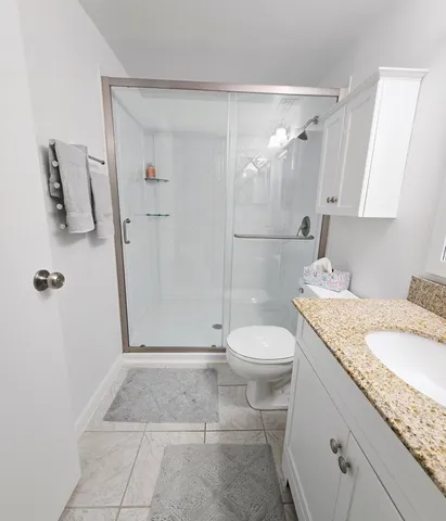 a bathroom with a granite countertop sink toilet and shower