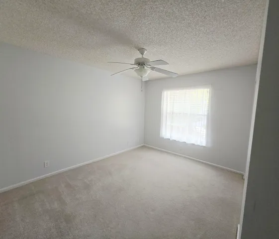 an empty room with a window and a fan
