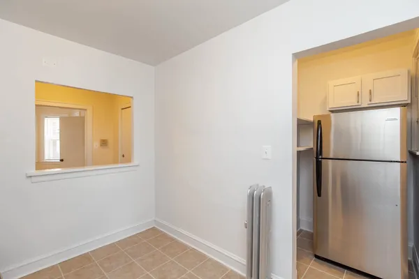 a view of a room with a refrigerator and wooden floor