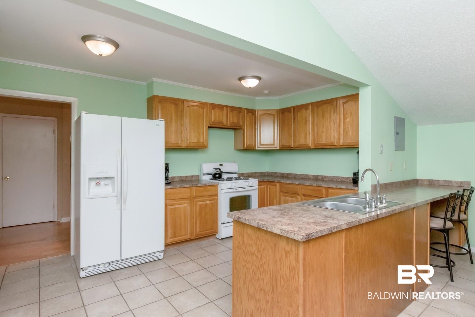 1321 Rainbow Drive West Mobile, AL 36693 - Photo 9 of 48 Kitchen with kitchen peninsula, light tile patterned floors, crown molding, sink, and white appliances