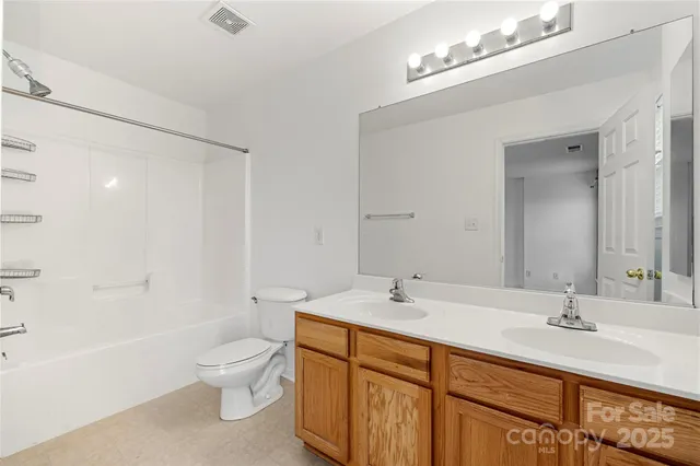 a bathroom with a double vanity sink toilet mirror and bathtub