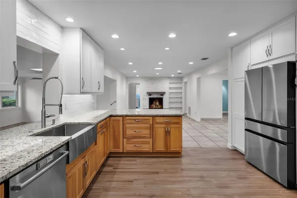 a large kitchen with stainless steel appliances granite countertop a large counter top a sink and a refrigerator