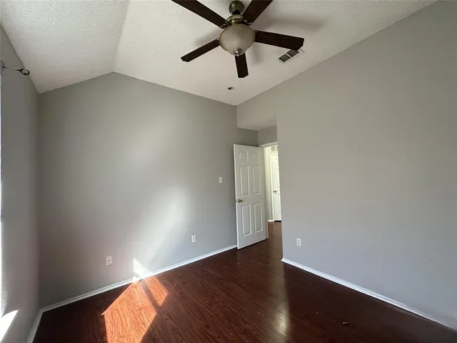 an empty room with wooden floor and ceiling fan