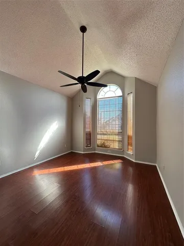 a view of an empty room with wooden floor ceiling fan and a window