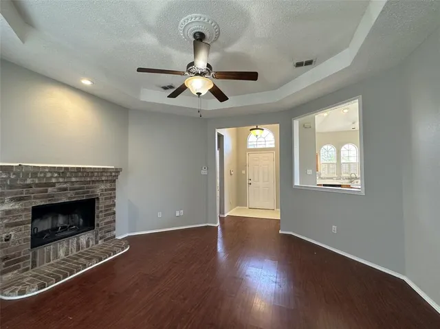 an empty room with wooden floor fireplace and windows