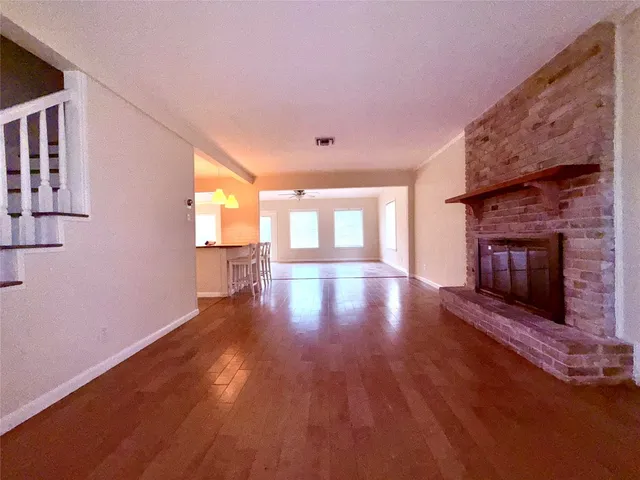 a view of an empty room with wooden floor and a fireplace
