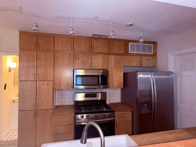 a kitchen with stainless steel appliances a refrigerator and a stove top oven