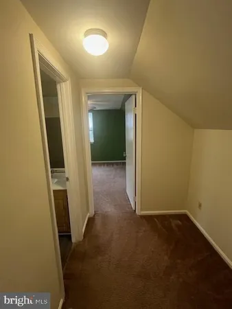 a view of an empty room with a window and a kitchen