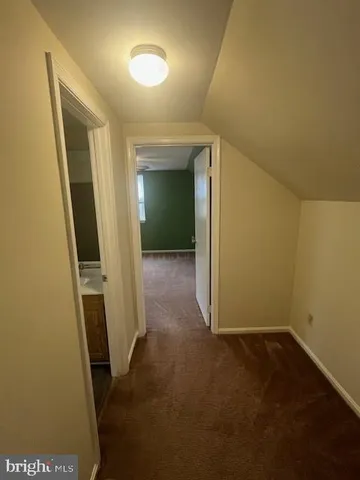 a view of an empty room with a window and a kitchen