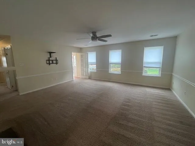 en empty room with windows and ceiling fan