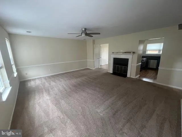 an empty room with windows fireplace and a kitchen view